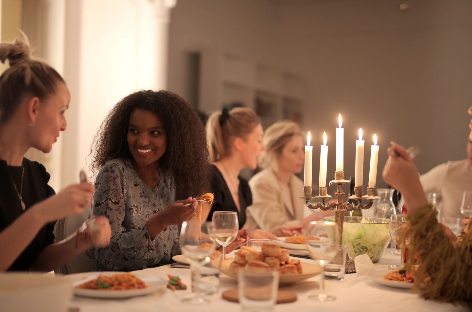 Des amies réunies autour d'une table, verres de vin et plats à partager